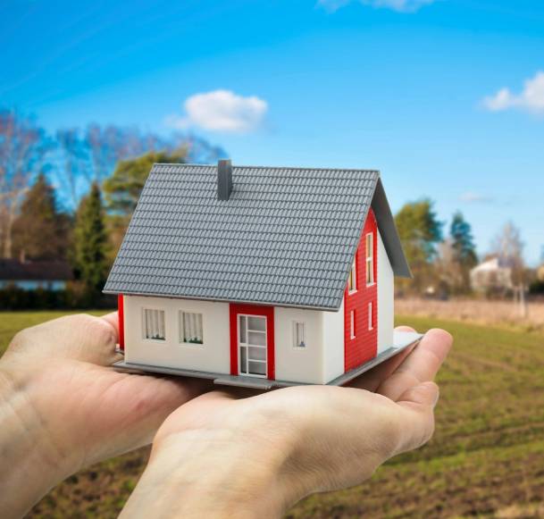 A person holding a small house in their hands.