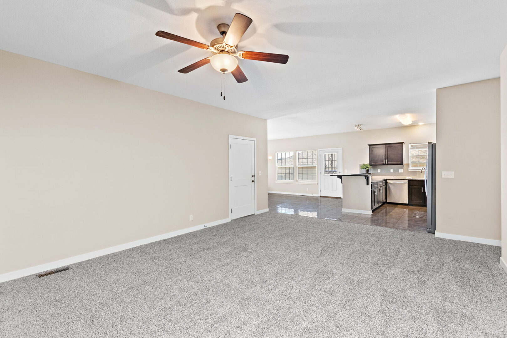 A living room with a ceiling fan and a large open floor plan.