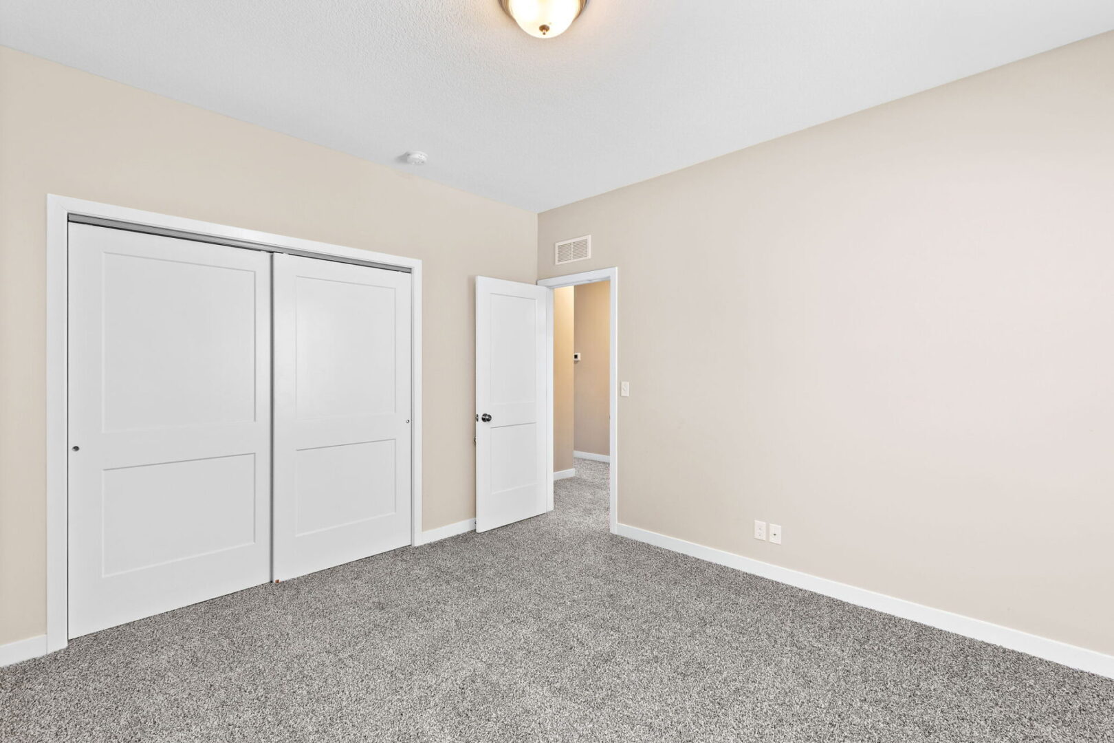 A bedroom with two closets and a door open.