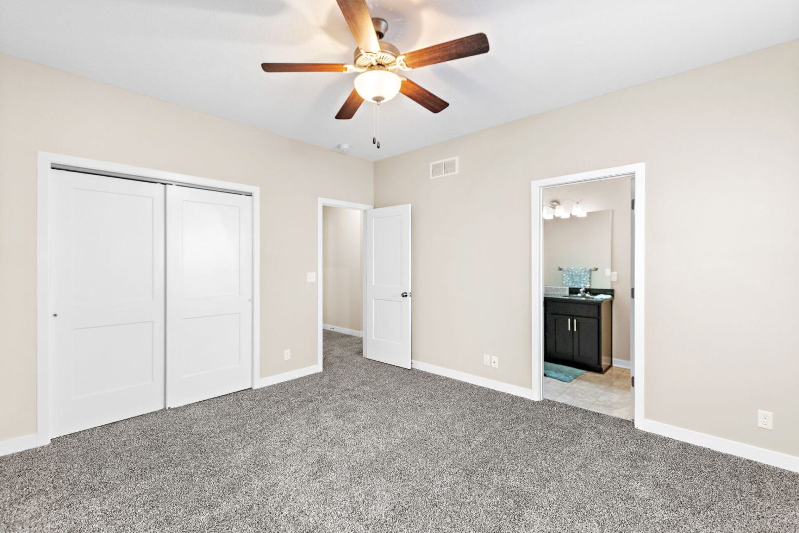 A bedroom with two closets and a ceiling fan.