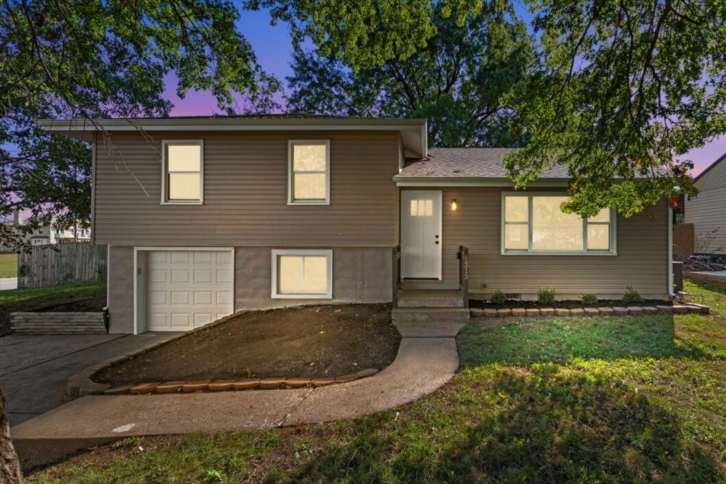 A house with a driveway and trees in the background