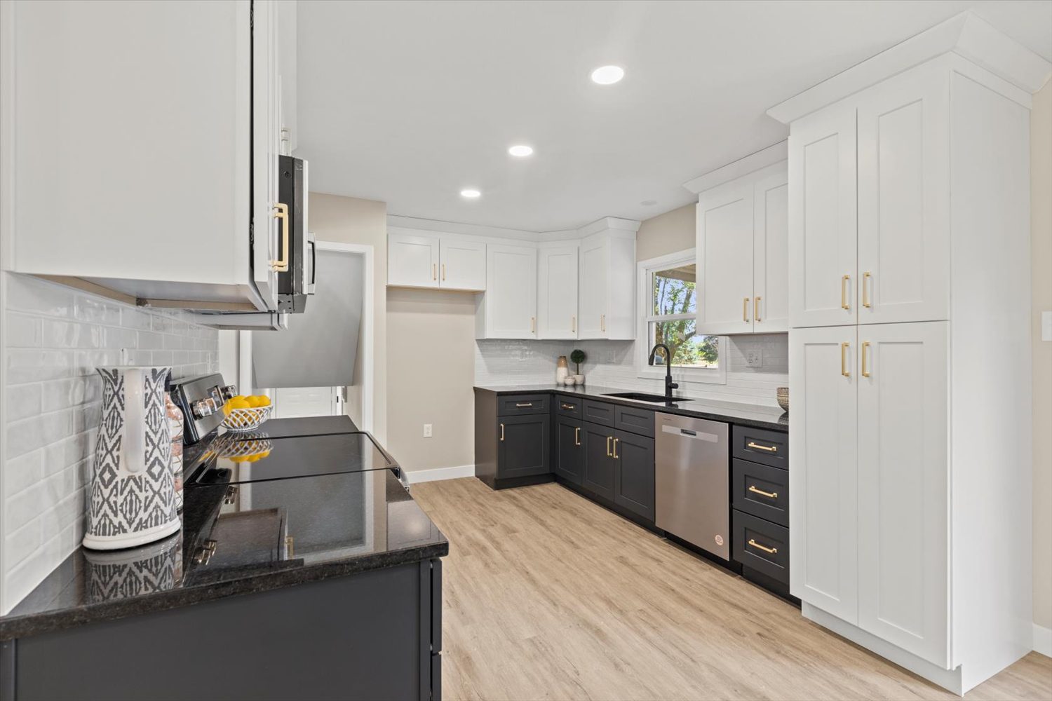 A kitchen with white cabinets and black counter tops.