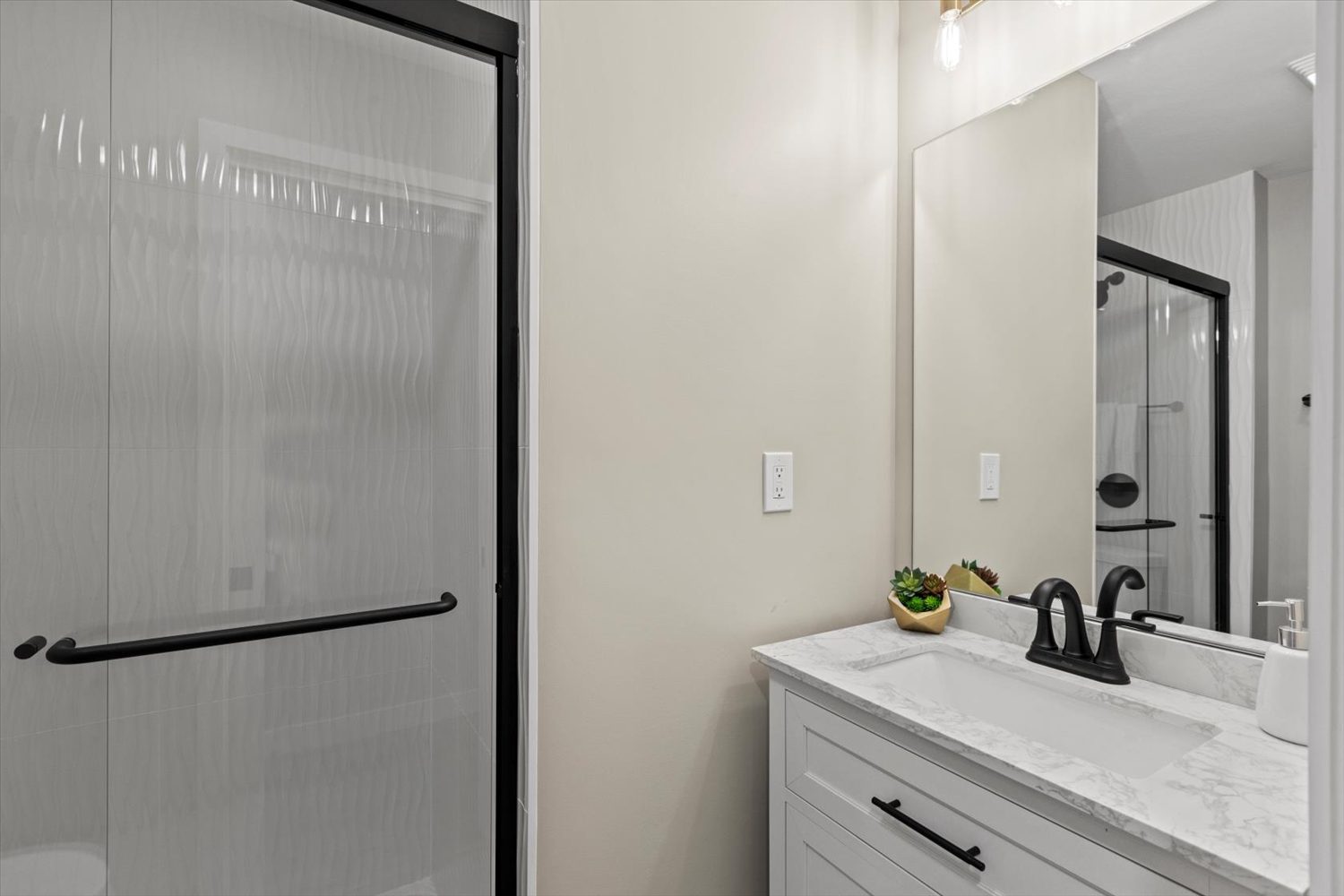 A bathroom with a sink, mirror and shower.