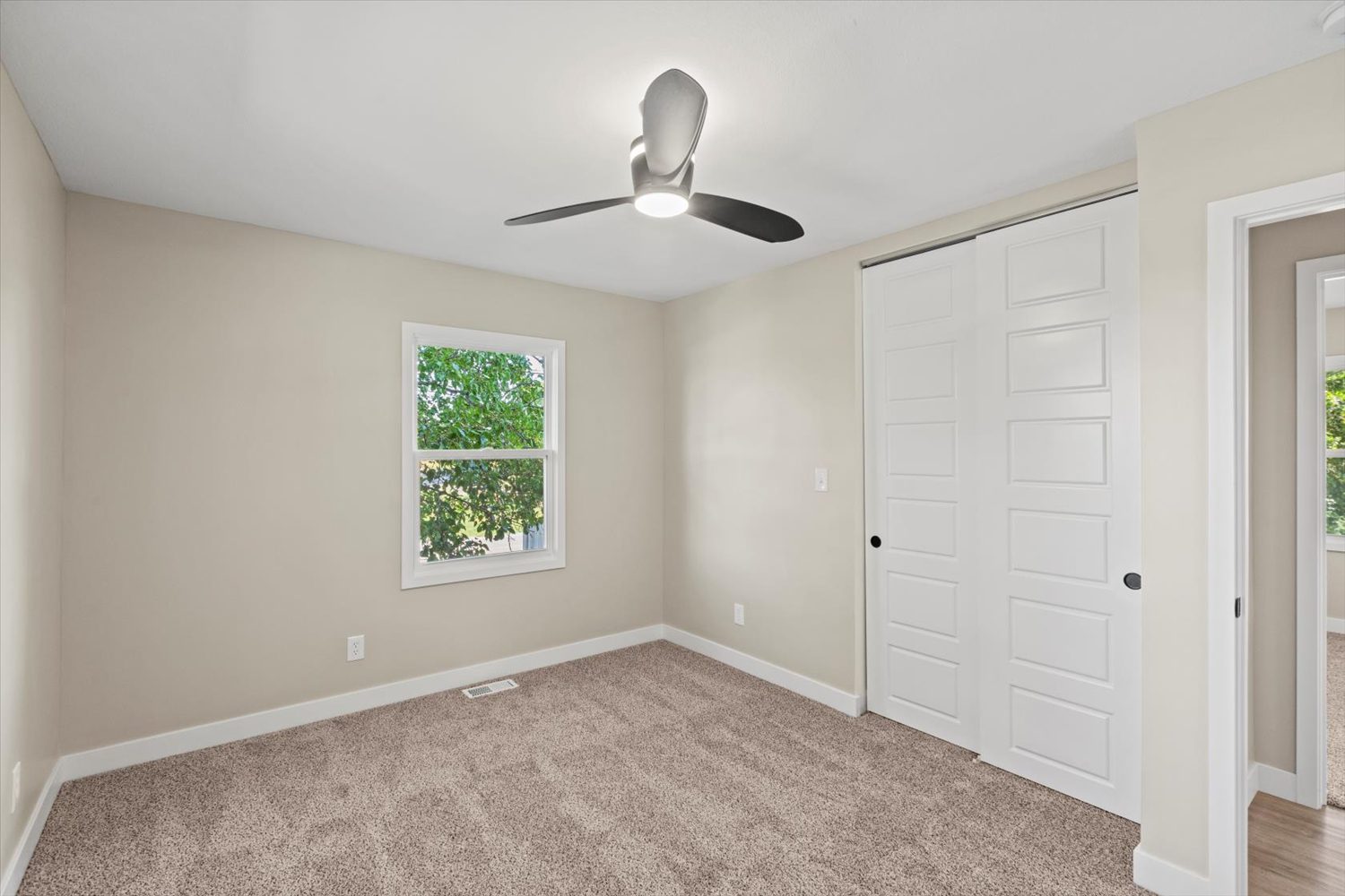 A bedroom with a ceiling fan and a door.