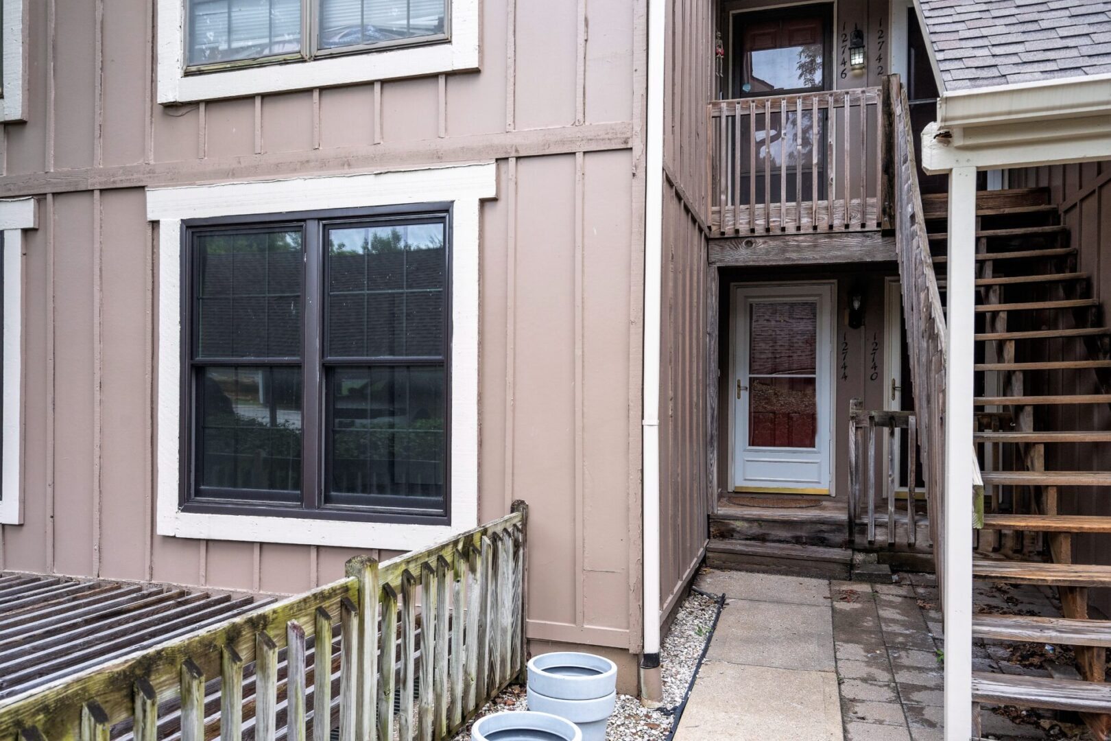 A building with a fence and stairs leading to the front door.