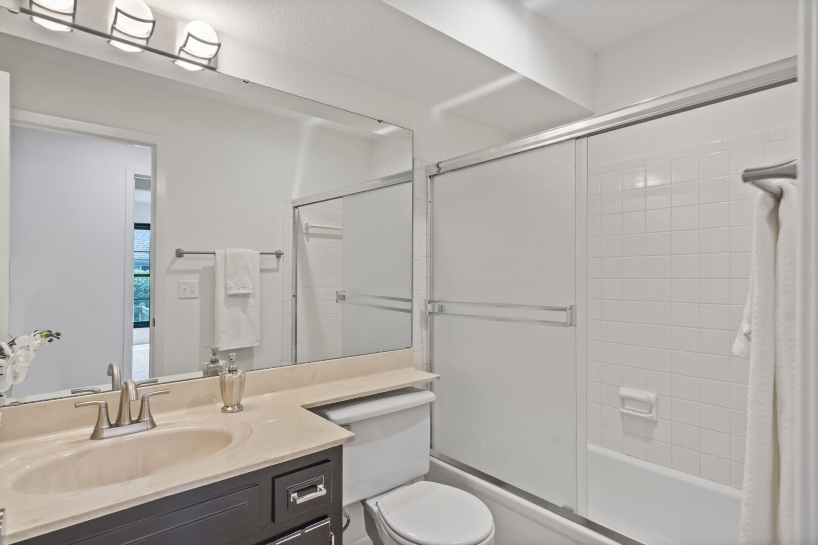 A bathroom with white walls and beige counter tops.