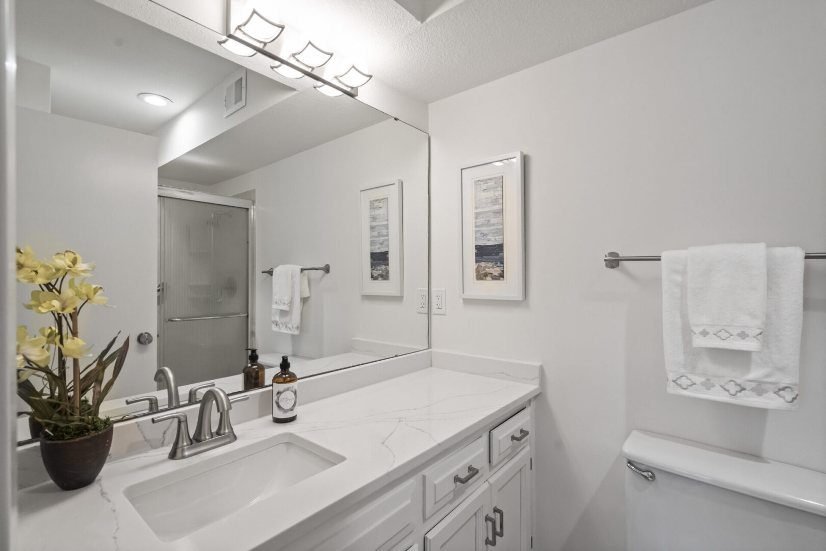 A bathroom with white cabinets and a large mirror.