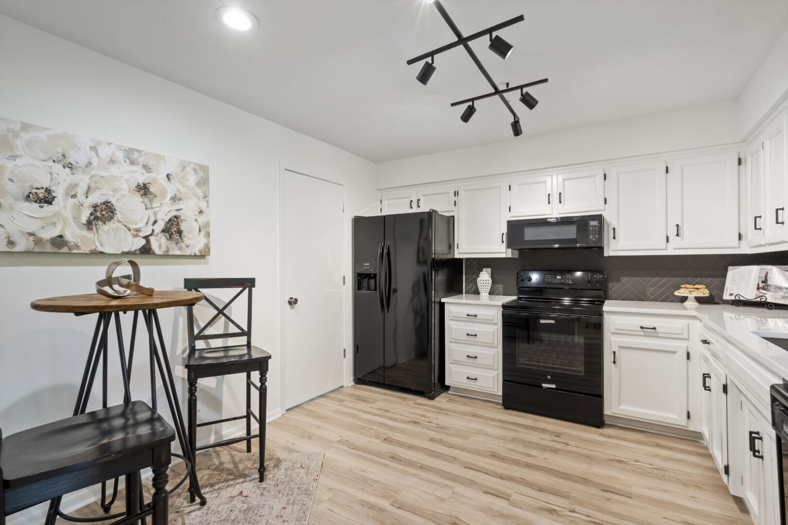 A kitchen with black appliances and white cabinets.