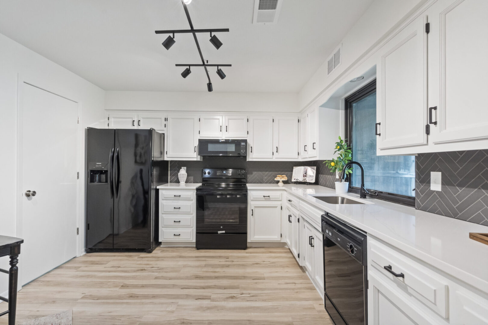 A kitchen with white cabinets and black appliances.