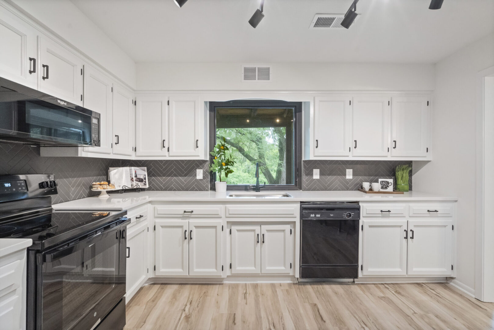 A kitchen with white cabinets and black appliances.